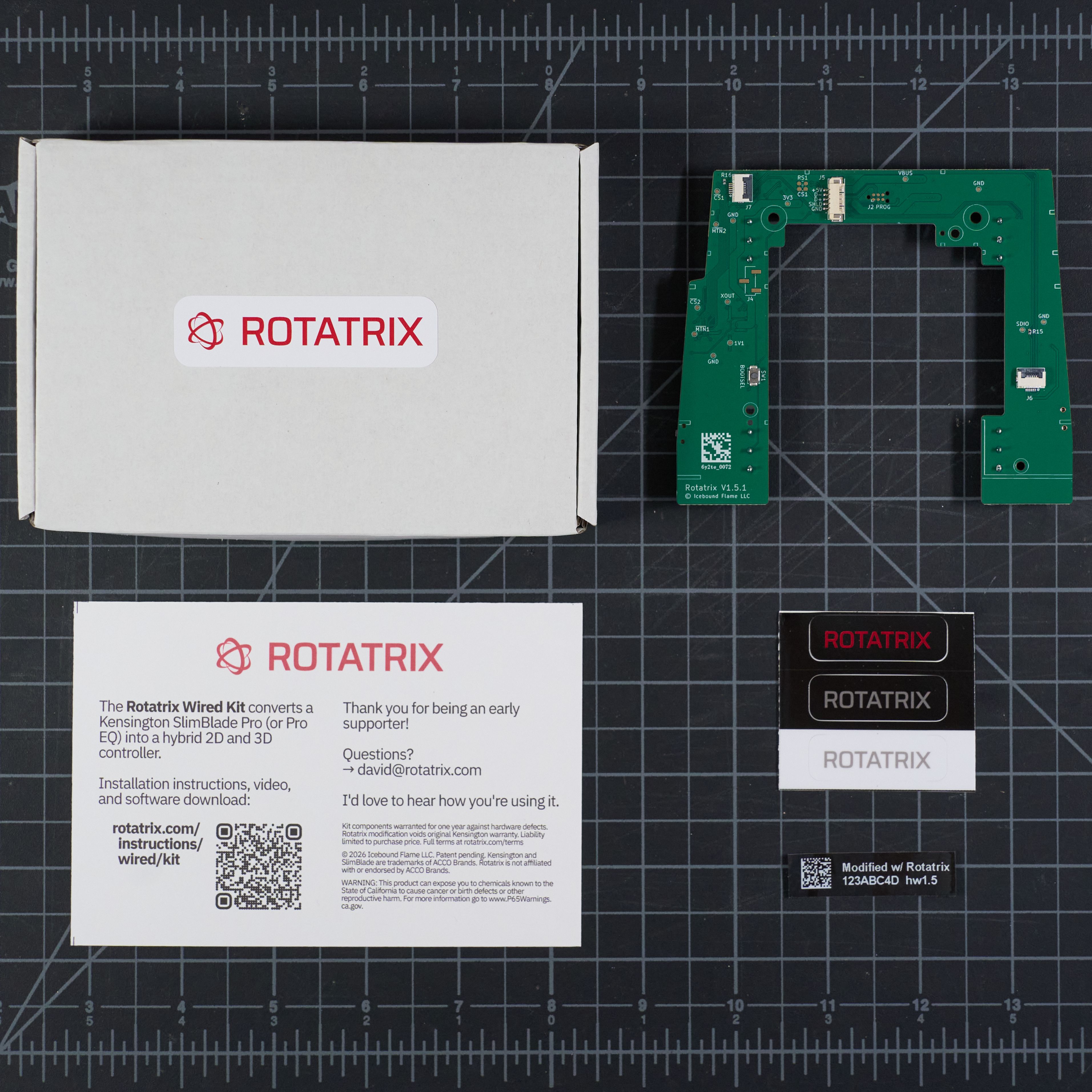 The Rotatrix Wired kit laid out — the board, info card, three-color decal sheet, and serial label, with the box